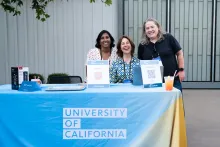 UC Tech 2025 ambassadors (L to R), Azra Ayers, Laurel Skurko, Chris Patterson, smiling at a conference booth.