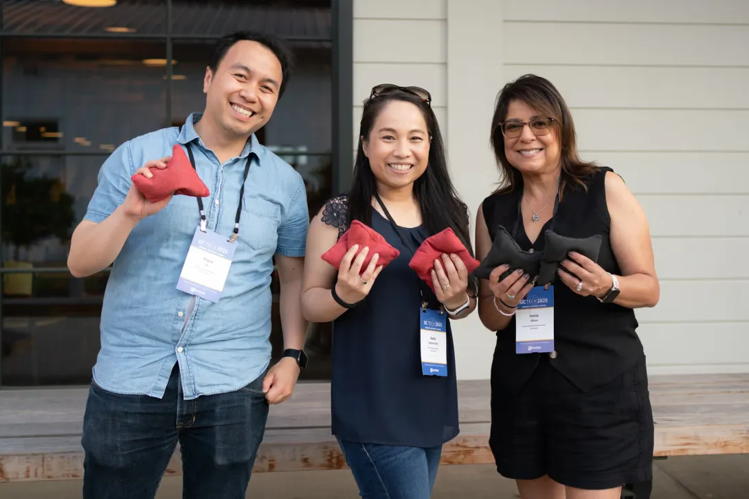 UC Tech 2025 attendees posing with bean bags after a game or cornhole.